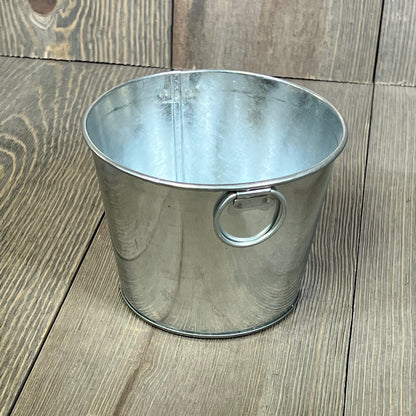 Mini galvanized bucket with handle on wooden surface, ideal for crafts or decor, size 4.5 x 3.5 inches.