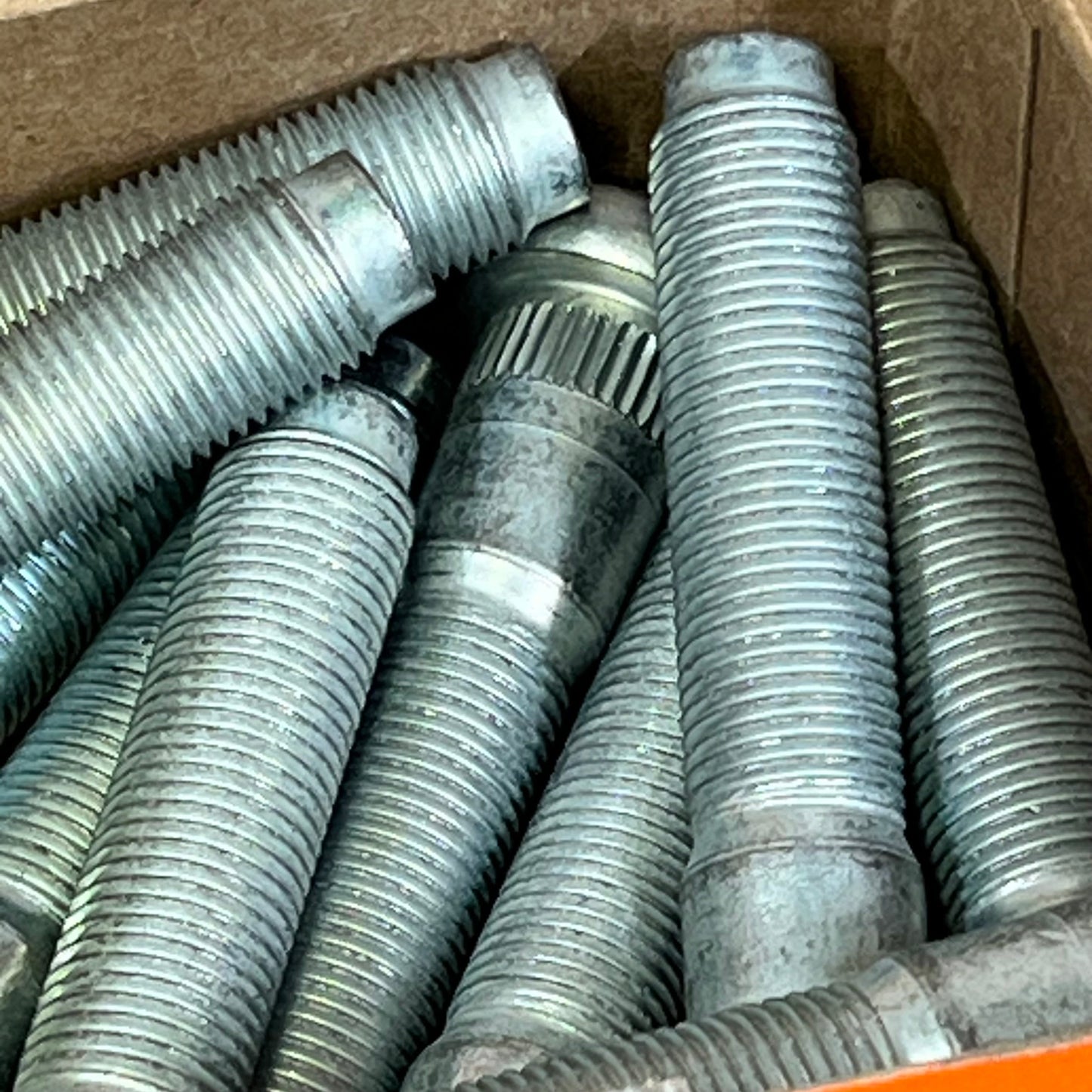 Close-up view of Dorman 610-383 serrated wheel studs, showcasing robust threads for select Dodge models.