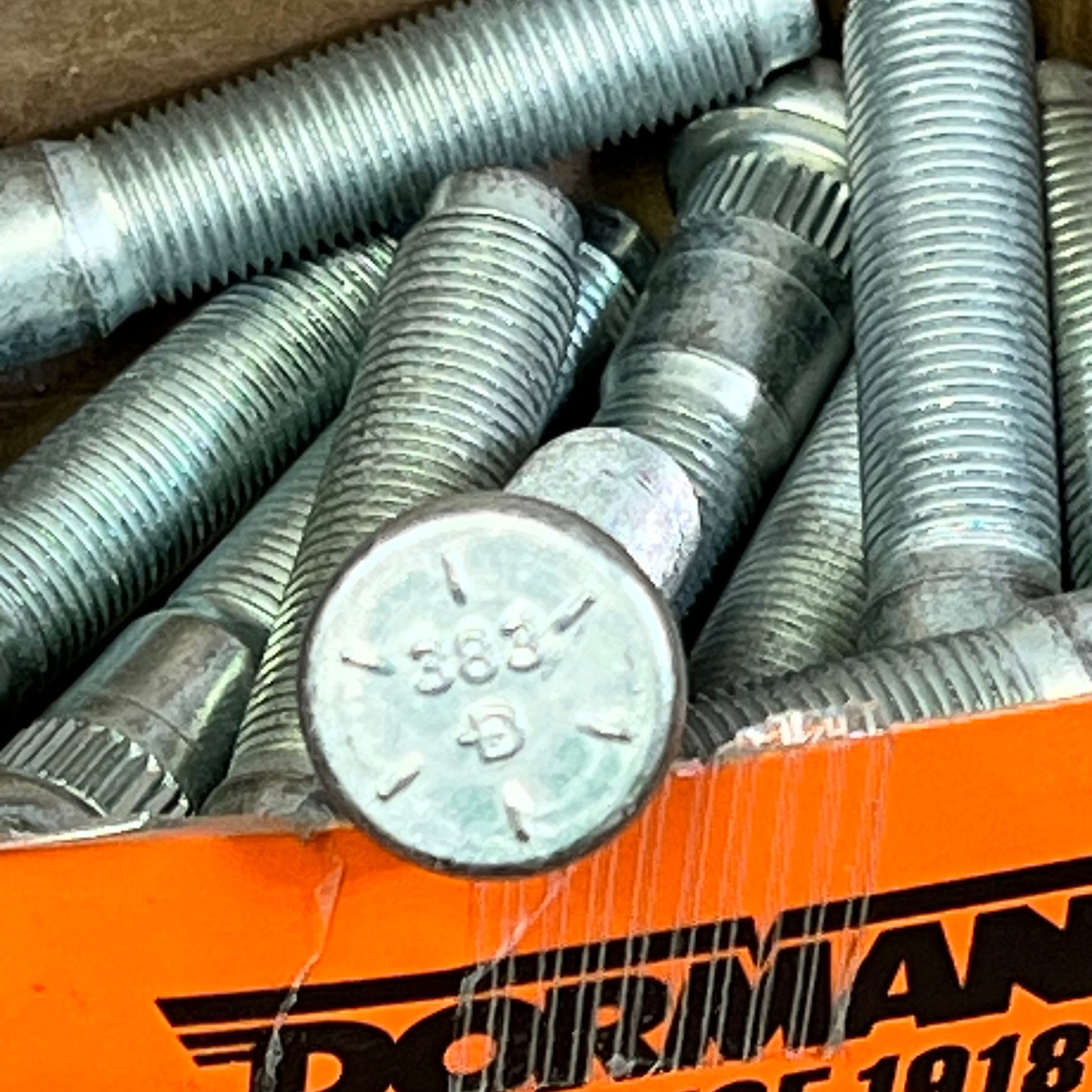 Dorman 610-383 serrated wheel studs, 9/16-18 size, in a box for Dodge models, showcasing knurl and length details.