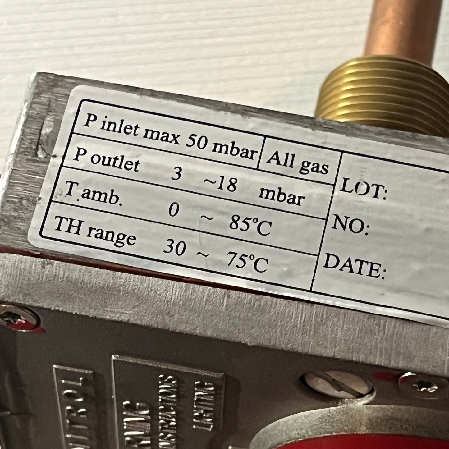 Close-up view of a gas water heater valve label, showing pressure and temperature specifications for accurate control.