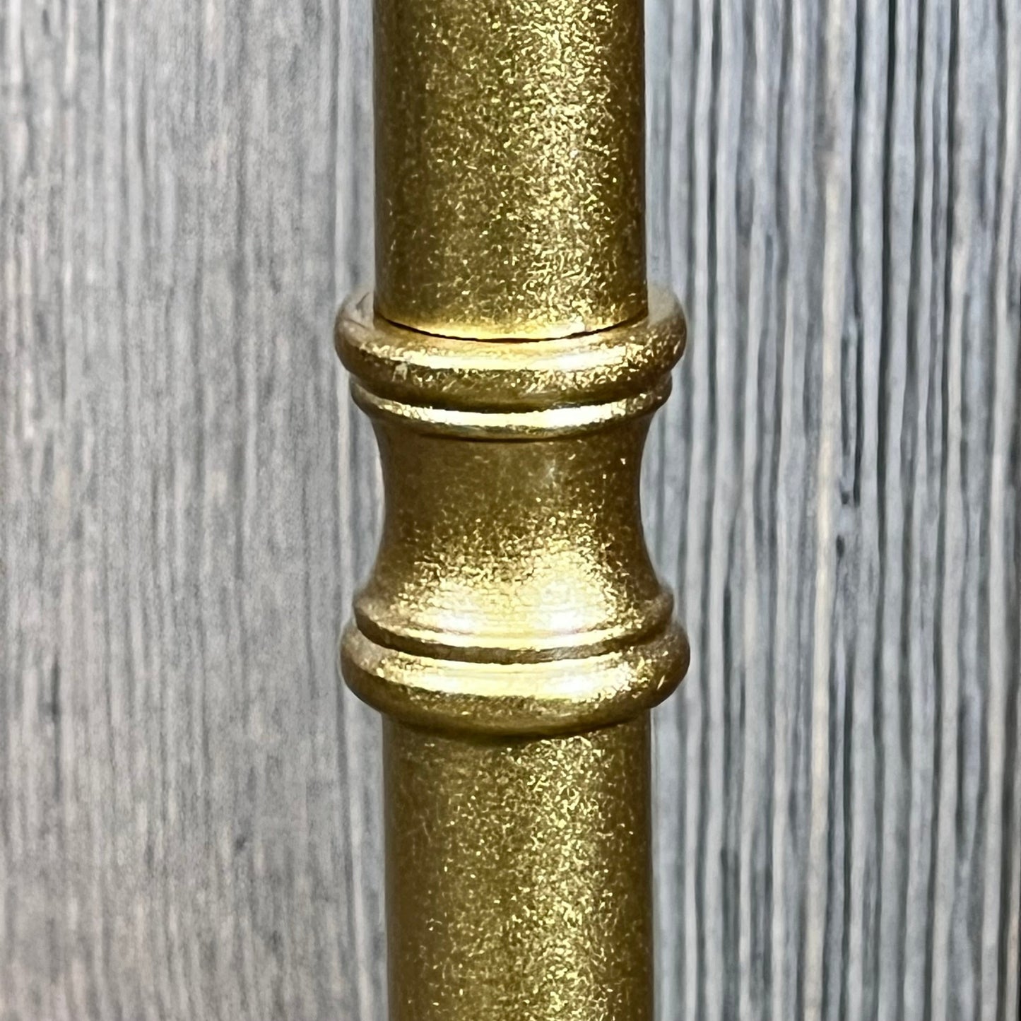 Close-up of the elegant gold stand of a rechargeable rattan cordless table lamp, showcasing its textured finish.