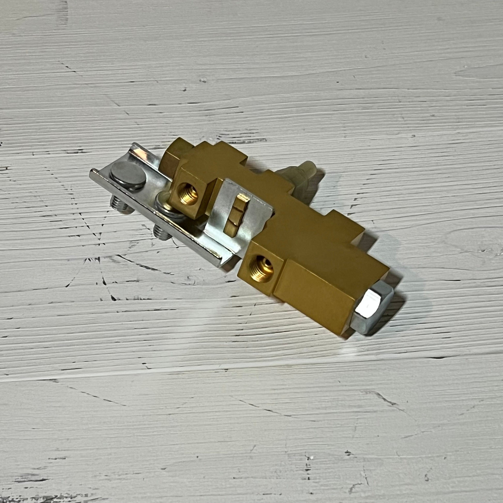 Gold and silver brake proportioning valve for Ford Mustang and Falcon, 1964-1970, resting on a white wooden surface.