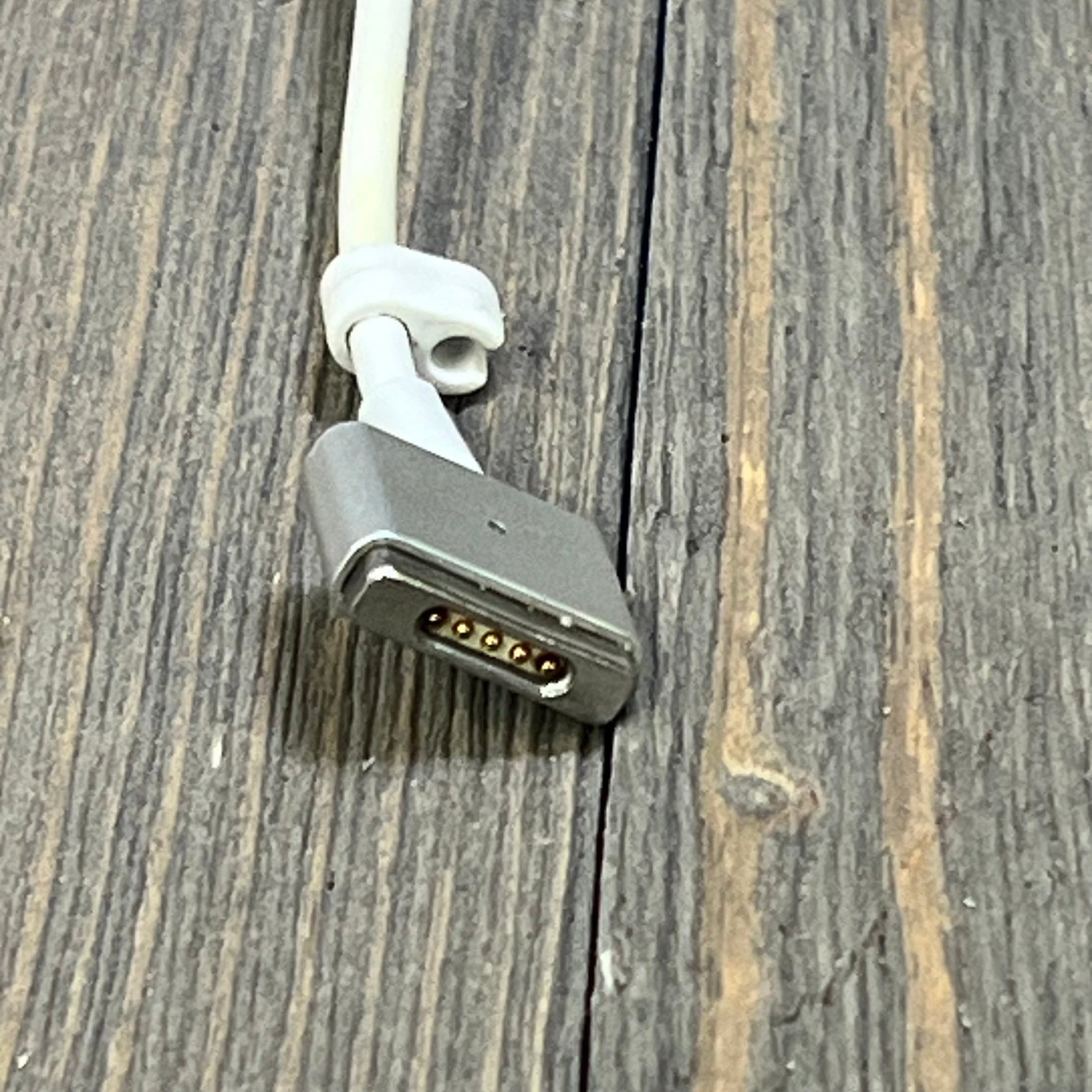 Close-up of the 45W Mag2 T-Tip connector for the MacBook Air Charger on a wooden surface.