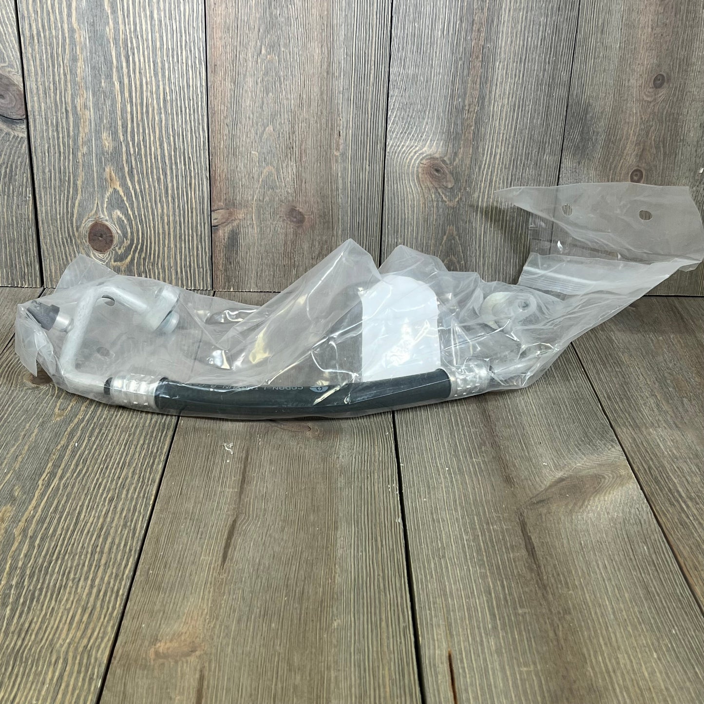 Premium A/C discharge line hose assembly for Jeep Wrangler 2007-2011, shown in protective packaging.