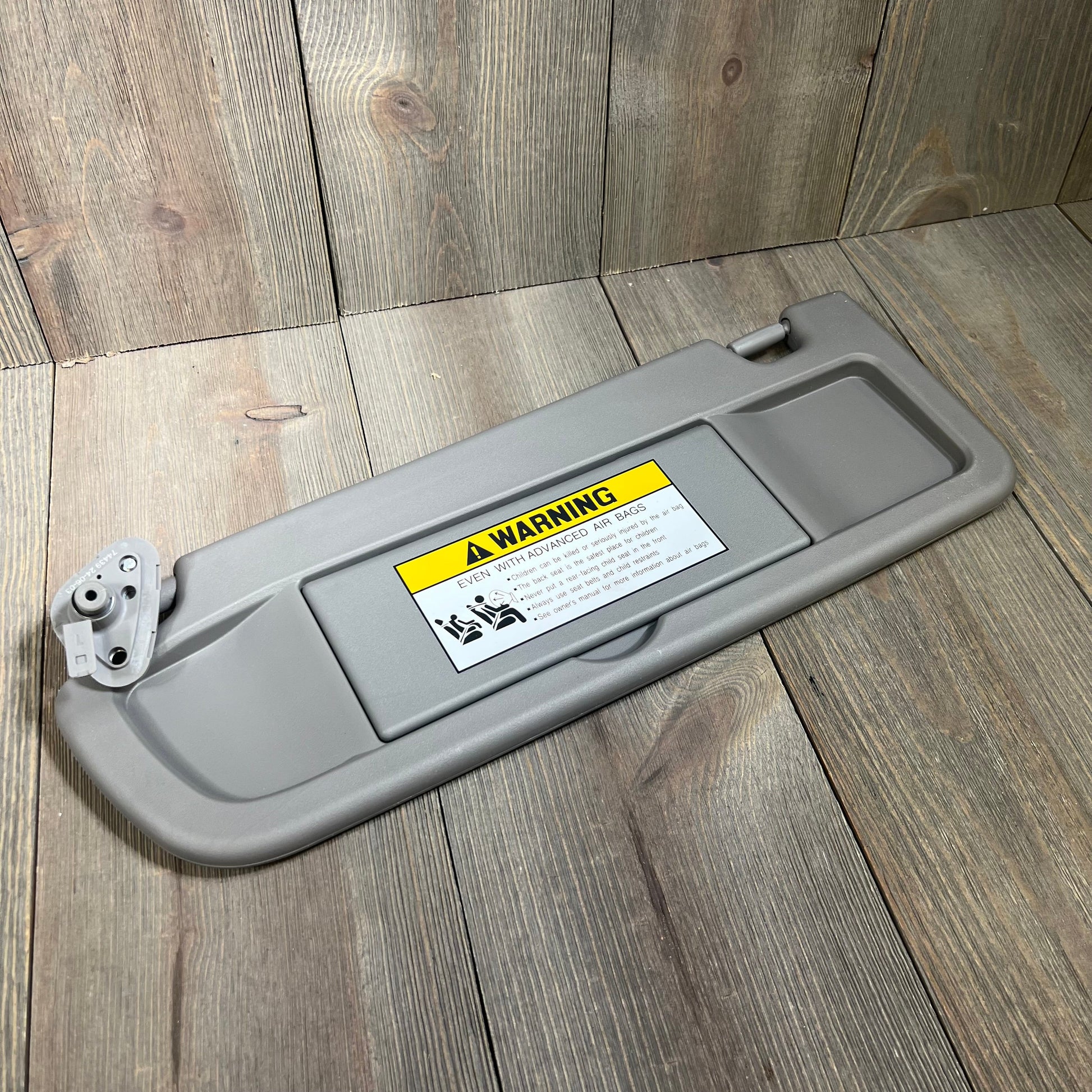 Gray Dorman 74439 driver side sun visor for Honda models, featuring warning label and sturdy construction.
