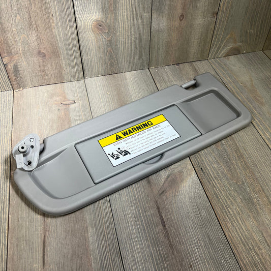 Gray Dorman 74439 driver side sun visor for Honda models, featuring warning label and sturdy construction.