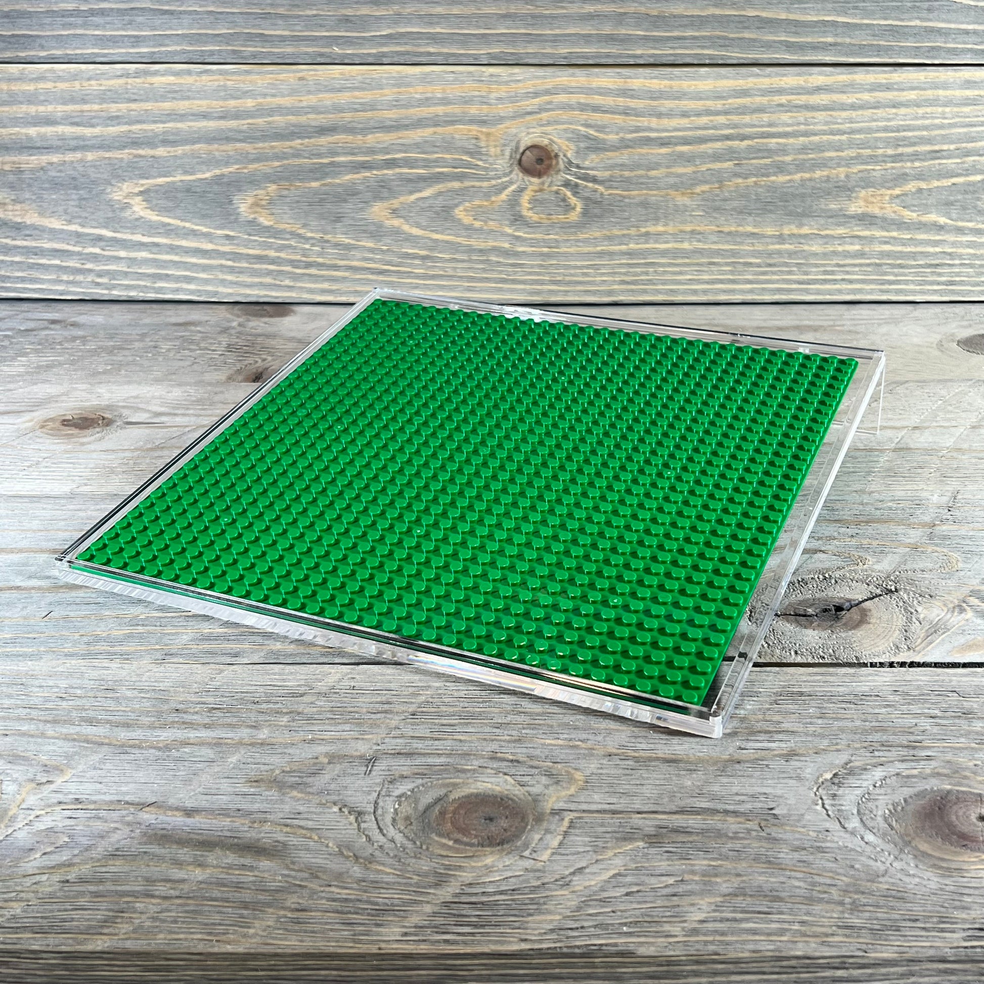 Green acrylic building brick display shelf, 10x10 inch, for minifigures, compatible with major brands, on wooden surface.