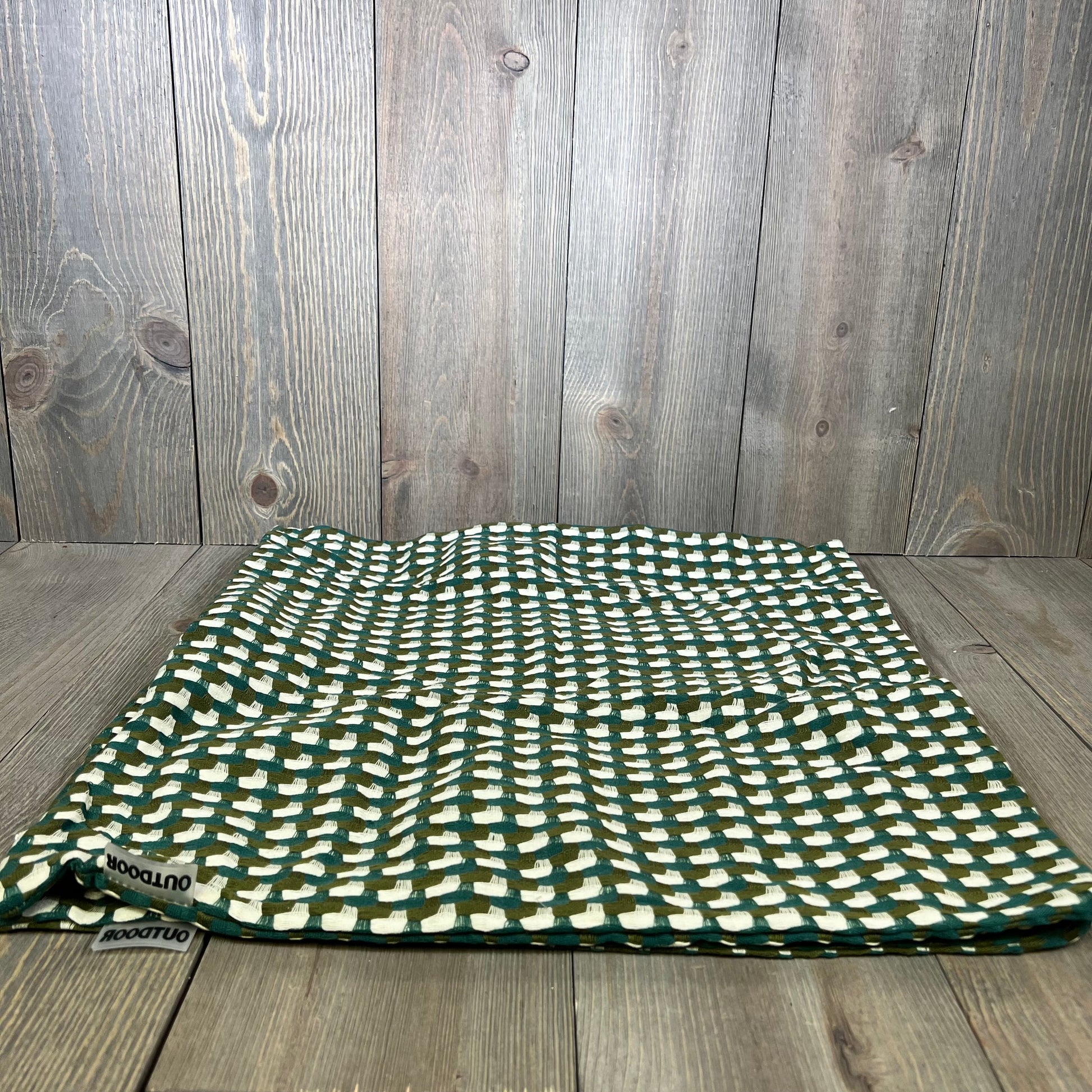 Green and white checkered outdoor pillow cover on wooden surface, ideal for patio or garden decor, 18x18 inches, waterproof.