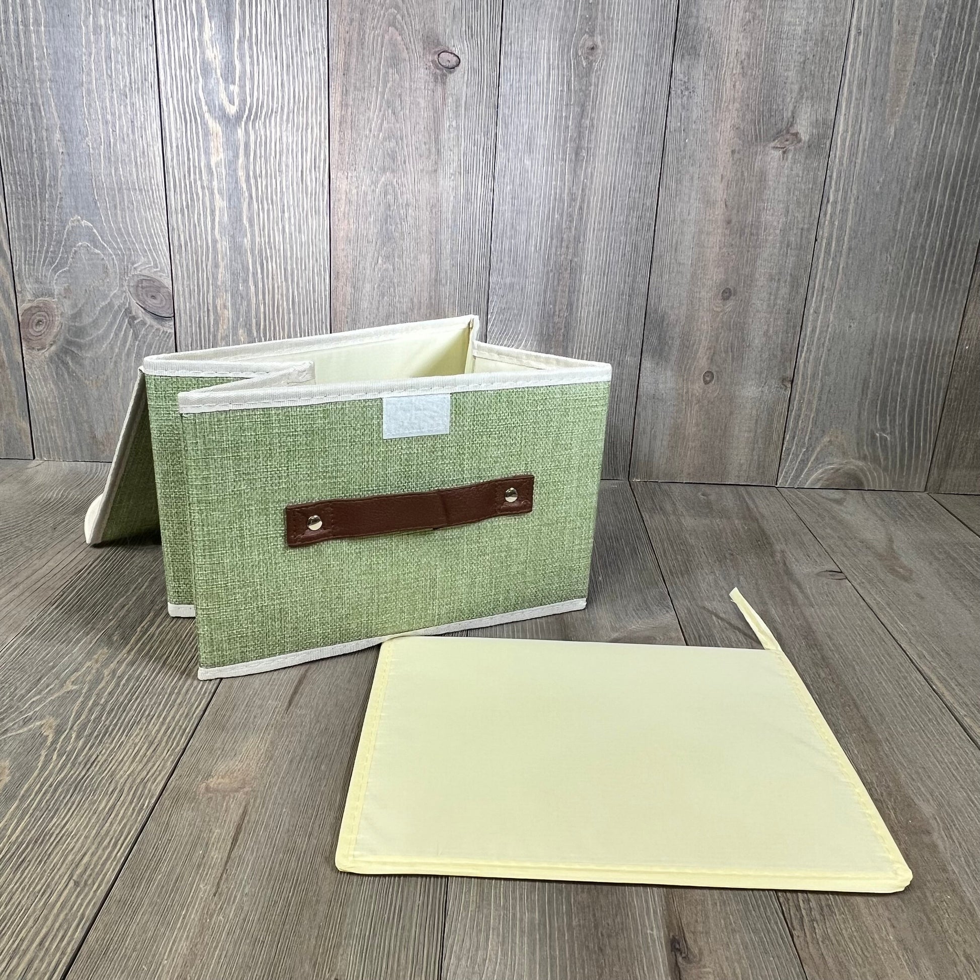 Green cotton linen storage box with faux leather handle and removable lid, ideal for organizing shelves and closets.