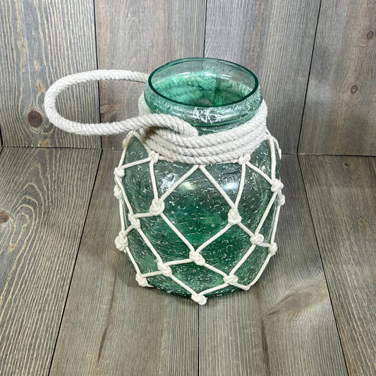 Coastal glass lantern with blue hue, wrapped in white rope, ideal for beach-themed decor, measures 7" x 7" x 15".