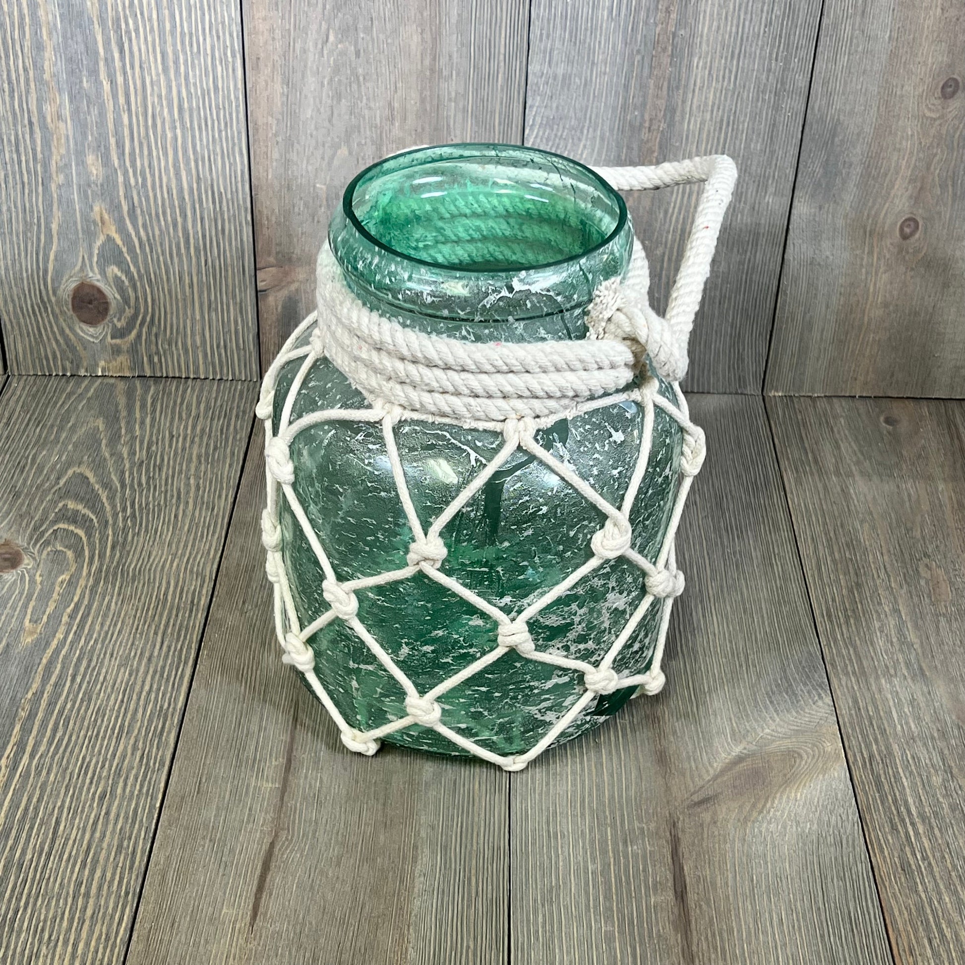 Coastal glass lantern with rope netting, ideal for nautical decor. Blue glass, 7"x7"x15", perfect for ambient lighting.