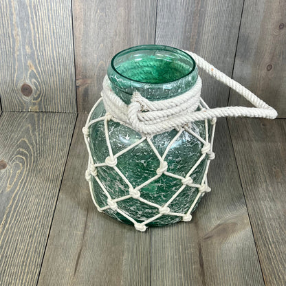 Coastal glass cylinder lantern with rope netting, featuring a textured blue finish for a nautical decor touch.