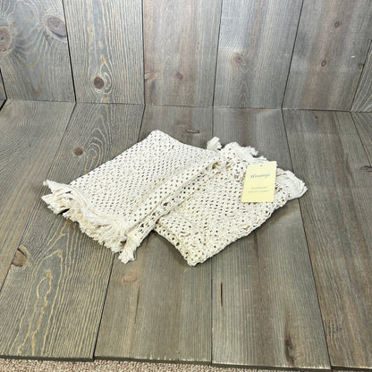 Cream beige macrame table mats with tassels on wooden surface, perfect for farmhouse dining decor.