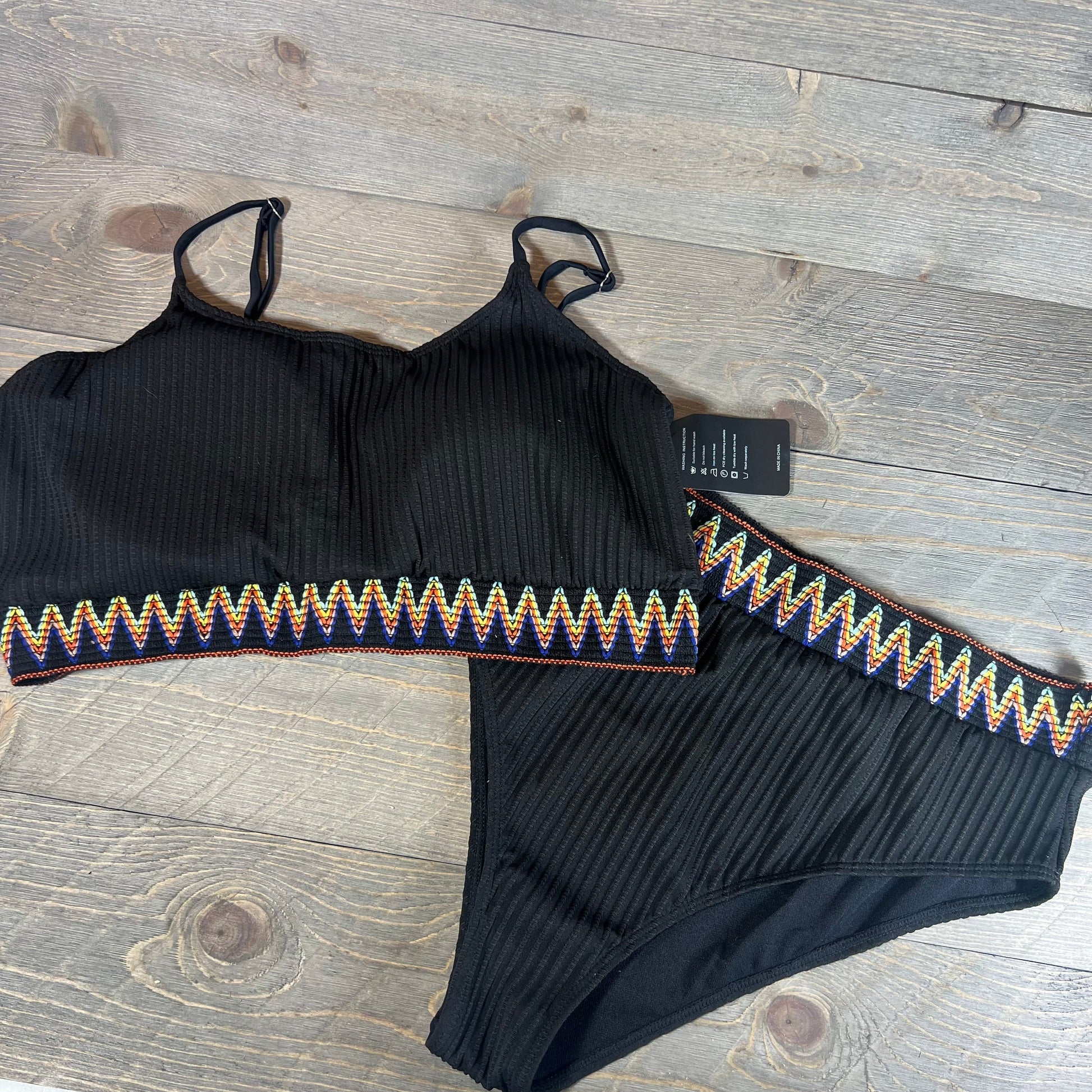 High waisted ribbed bikini set with colorful zigzag trim on a wooden background, size XXL.