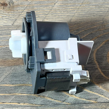 Kenmore Frigidaire dishwasher drain pump assembly on a wooden surface, showcasing its side profile and connector details.