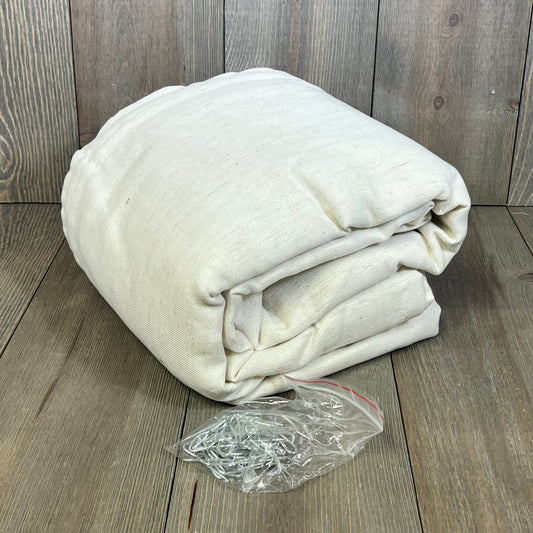 Cream linen semi-sheer curtains folded with hooks on wooden floor, ideal for wide windows and sliding doors.