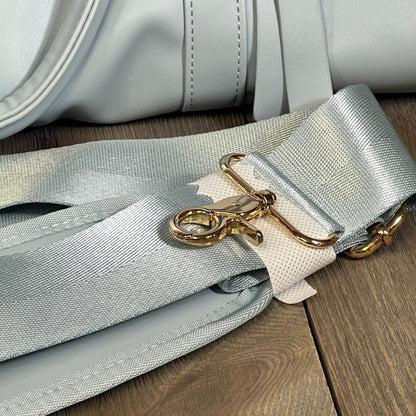 Blue convertible garment bag with durable gold-tone shoulder strap, ideal for stylish travel.