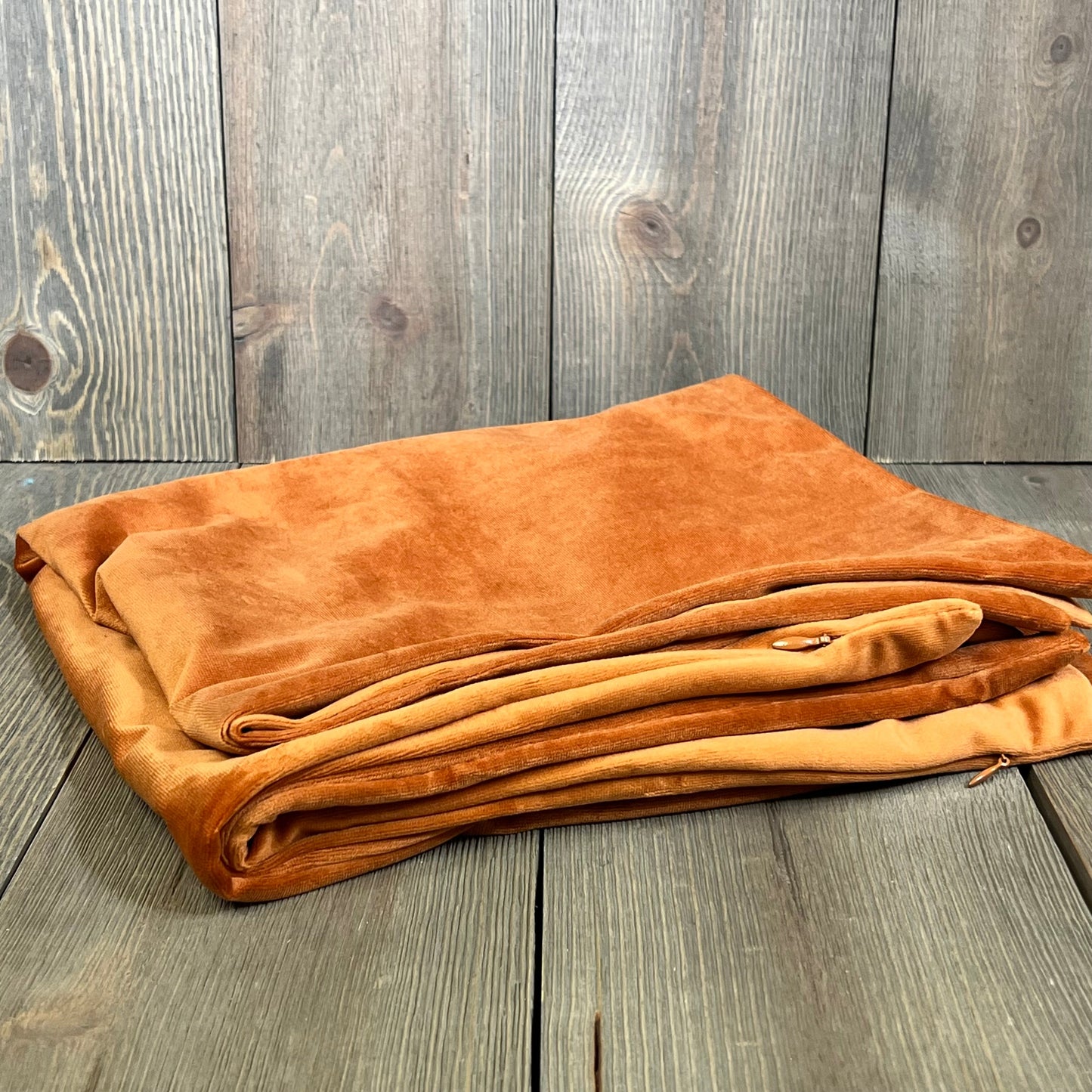 Rust velvet pillow covers 22x22 inch, folded on wooden surface. Luxurious and soft decorative cushion cases.
