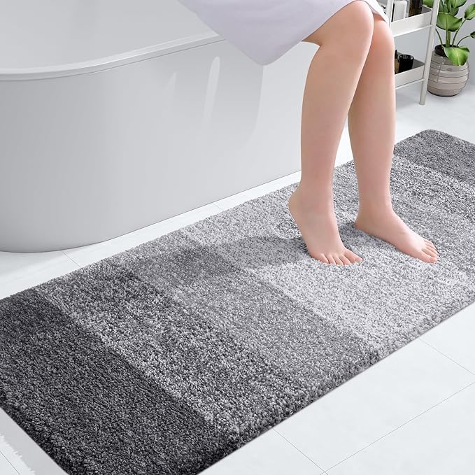 Grey OLANLY bathroom rug mat with plush shaggy texture, placed by a bathtub, showcasing its softness and absorbency.