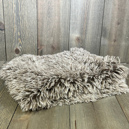 Shaggy ombre khaki faux fur pillow sham on wooden floor, showcasing soft plush texture for luxury home decor.