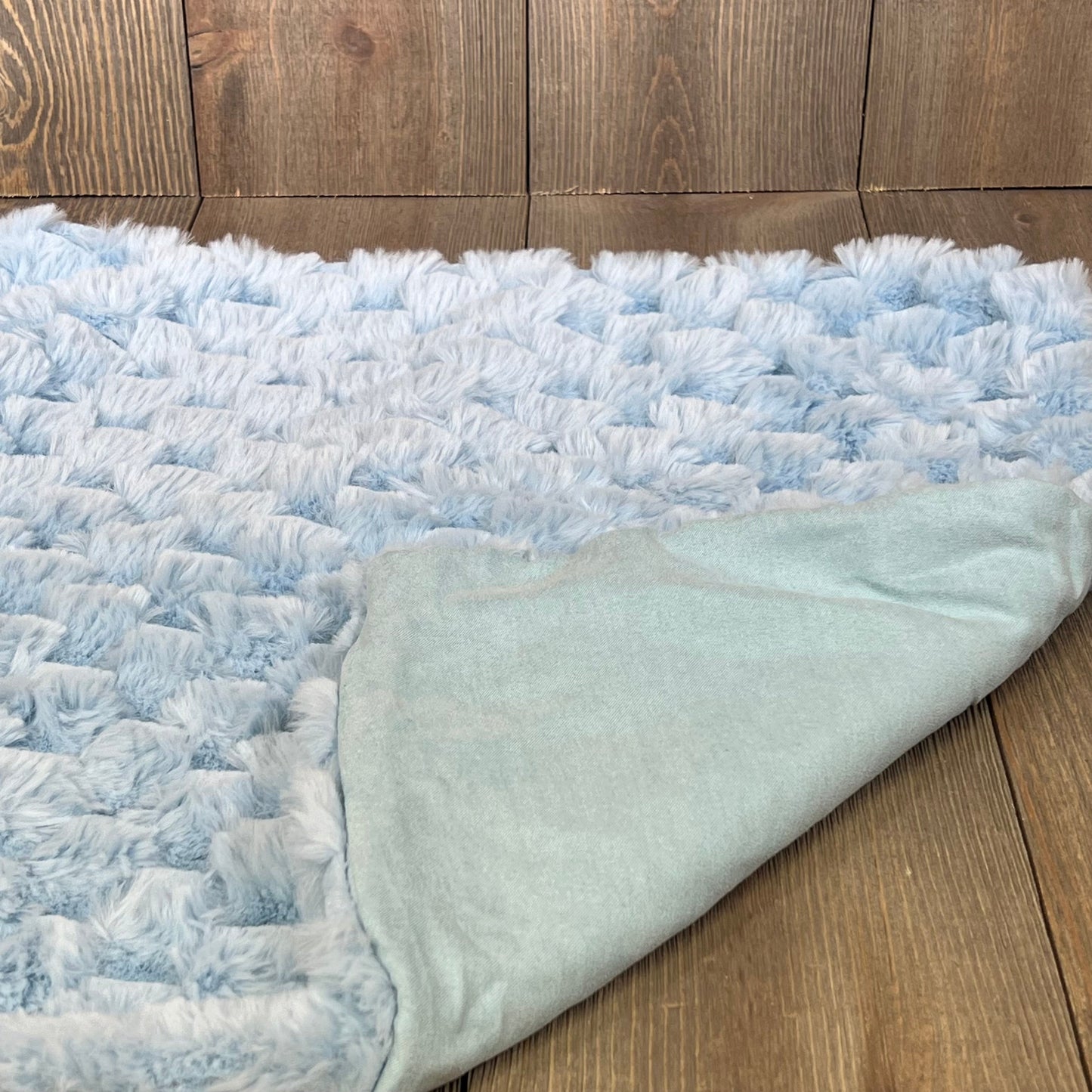 Light blue plush faux fur pillow cover showcasing soft texture on a wooden background, perfect for sofa or bed decor.