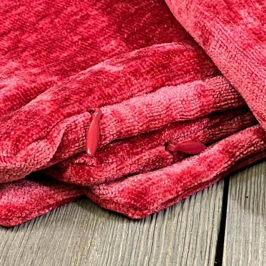 Bright red chenille throw pillow covers stacked on a rustic wooden floor, showcasing soft texture and vibrant color.