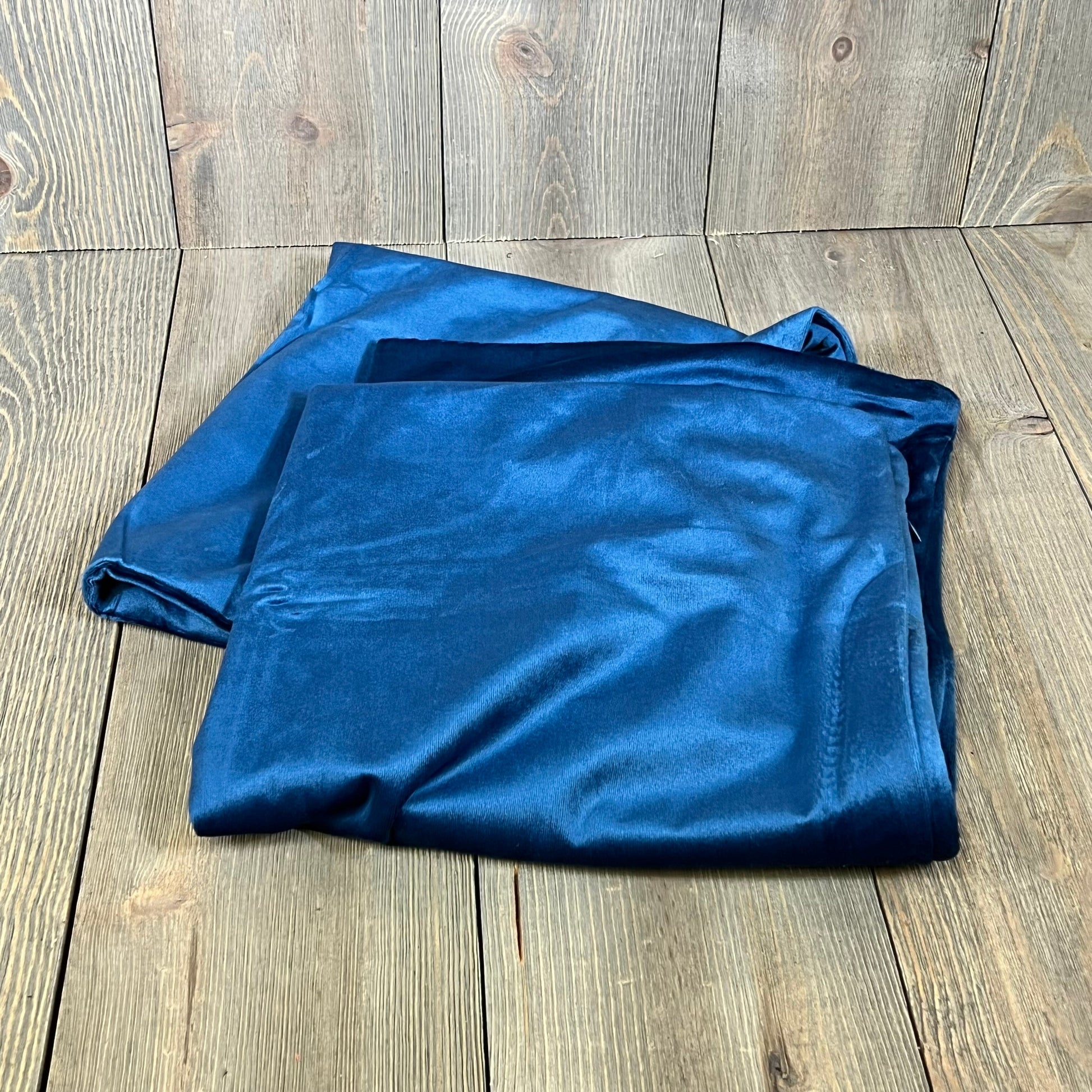 Dark blue velvet pillow covers on a wooden surface, showcasing luxurious texture and rich color, perfect for home decor.