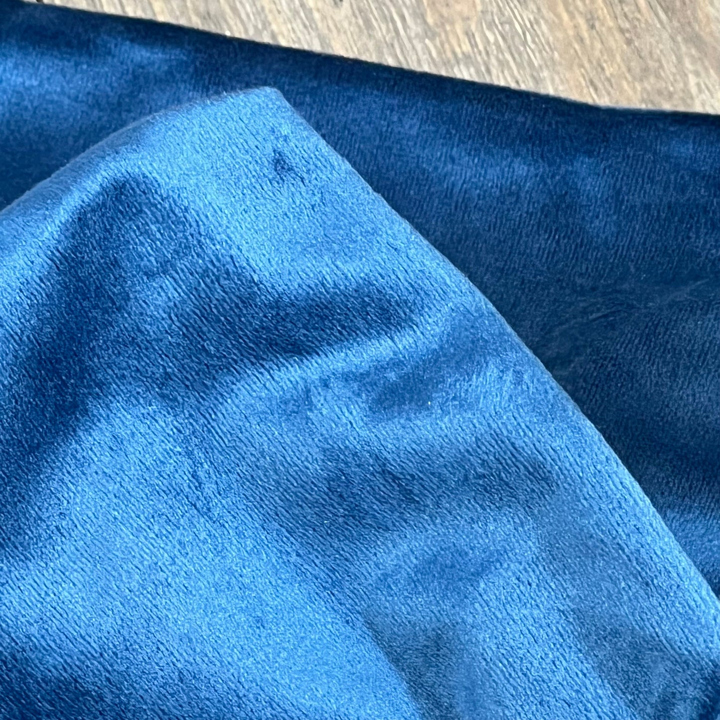 Dark blue velvet pillow cover close-up, highlighting soft, luxurious texture for enhancing couch or bed decor.