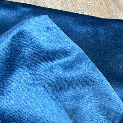Dark blue velvet pillow cover close-up, highlighting soft, luxurious texture for enhancing couch or bed decor.