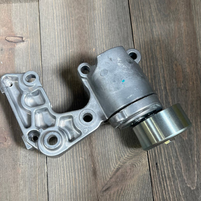 Replacement drive belt tensioner assembly for Toyota Lexus 3.5L 4.0L V6, part 16620-31040 on wooden background.