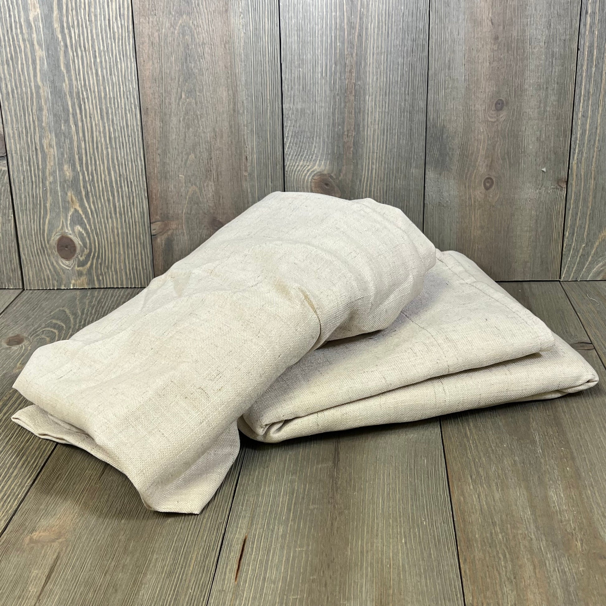 Folded H.VERSAILTEX linen curtains on wooden floor, showcasing soft, thick fabric in neutral tones, perfect for farmhouse decor.