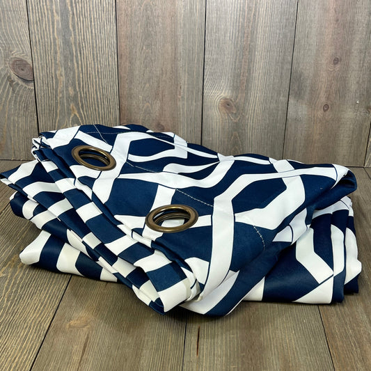 Navy and white trellis patterned curtains with grommets, folded on a wooden floor, ideal for modern living spaces.