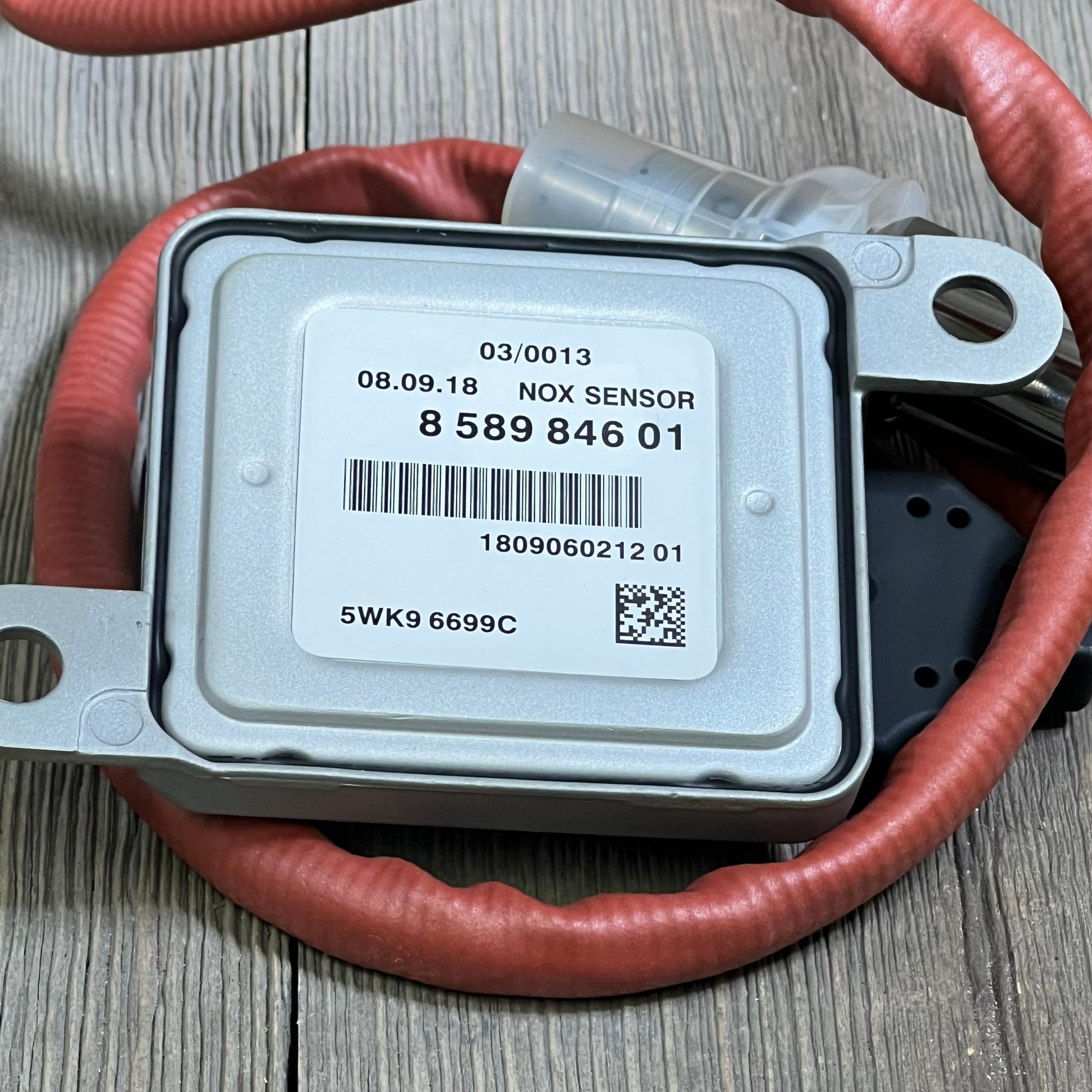 NOx sensor for BMW models with red wiring, labeled 858984601, enhances vehicle emission control efficiency.