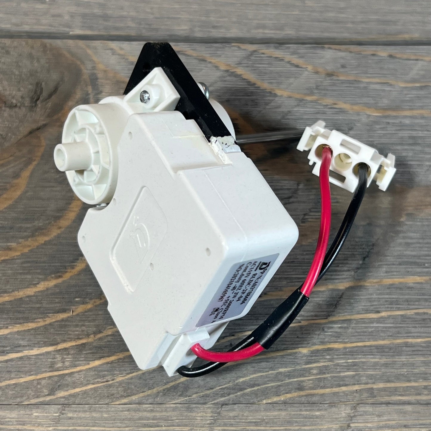OEM evaporator fan motor for Frigidaire and Kenmore refrigerators, model 5304514392, on a wooden surface.