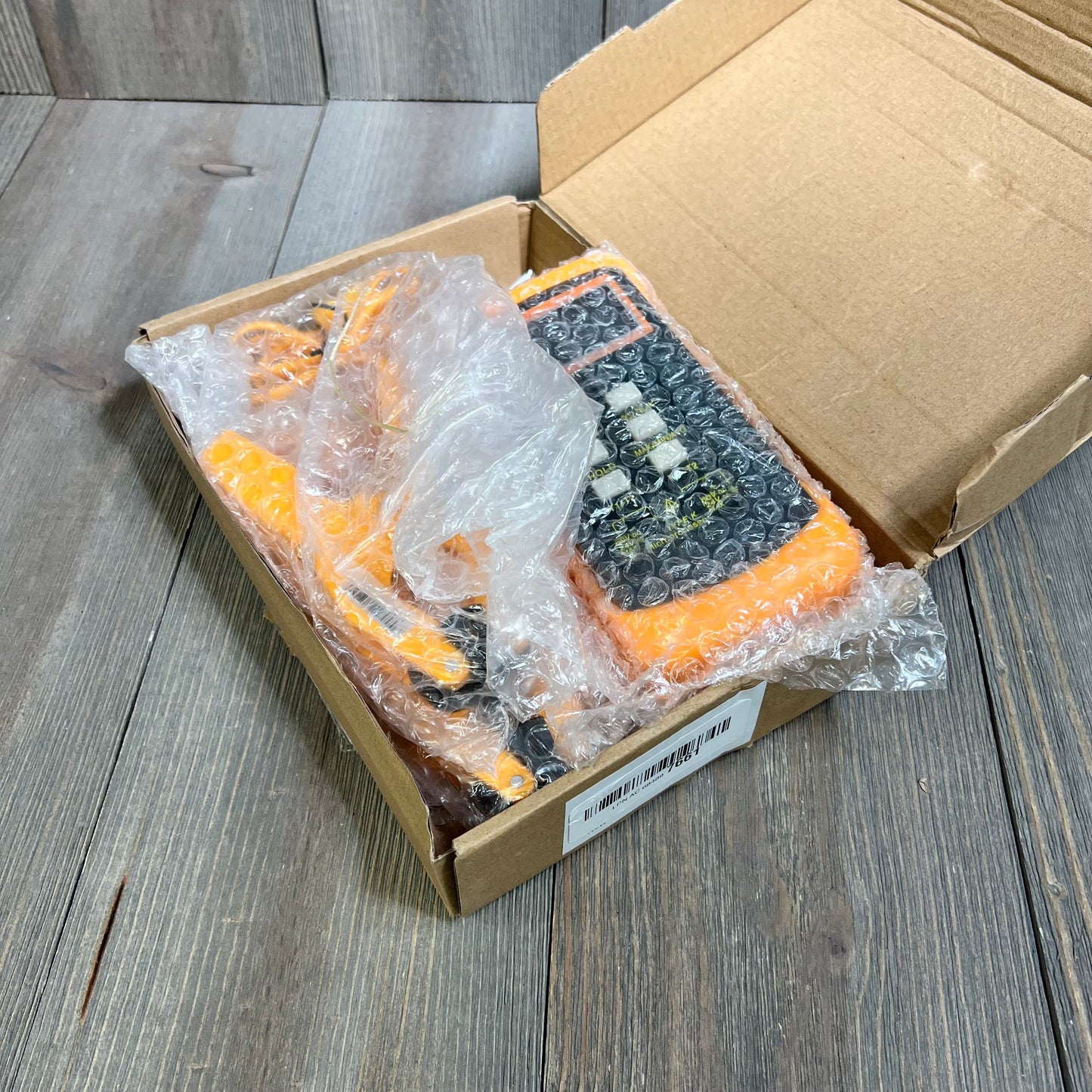 K Type Thermocouple Thermometer in open box, showing orange digital display and wired probes wrapped in bubble wrap.