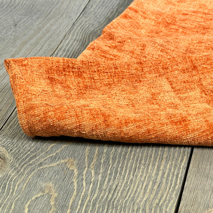 Rust chenille throw pillow cover in soft fabric, showcasing texture and vibrant color on a wooden floor background.