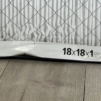 Close-up of Filtrete 18x18x1 MERV 12 air filter, showcasing pleated design and electrostatic material on wood floor.