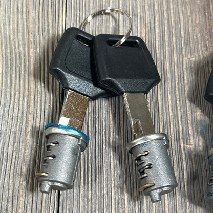 Durable metal lock cylinders and keys for Yakima car roof rack system components on a wooden surface.
