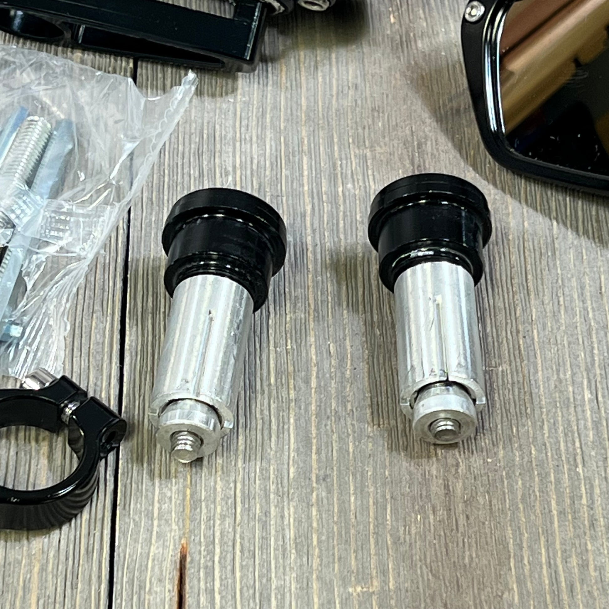 Black CNC aluminum alloy motorcycle bar end mirrors with mounting hardware on a wooden surface.