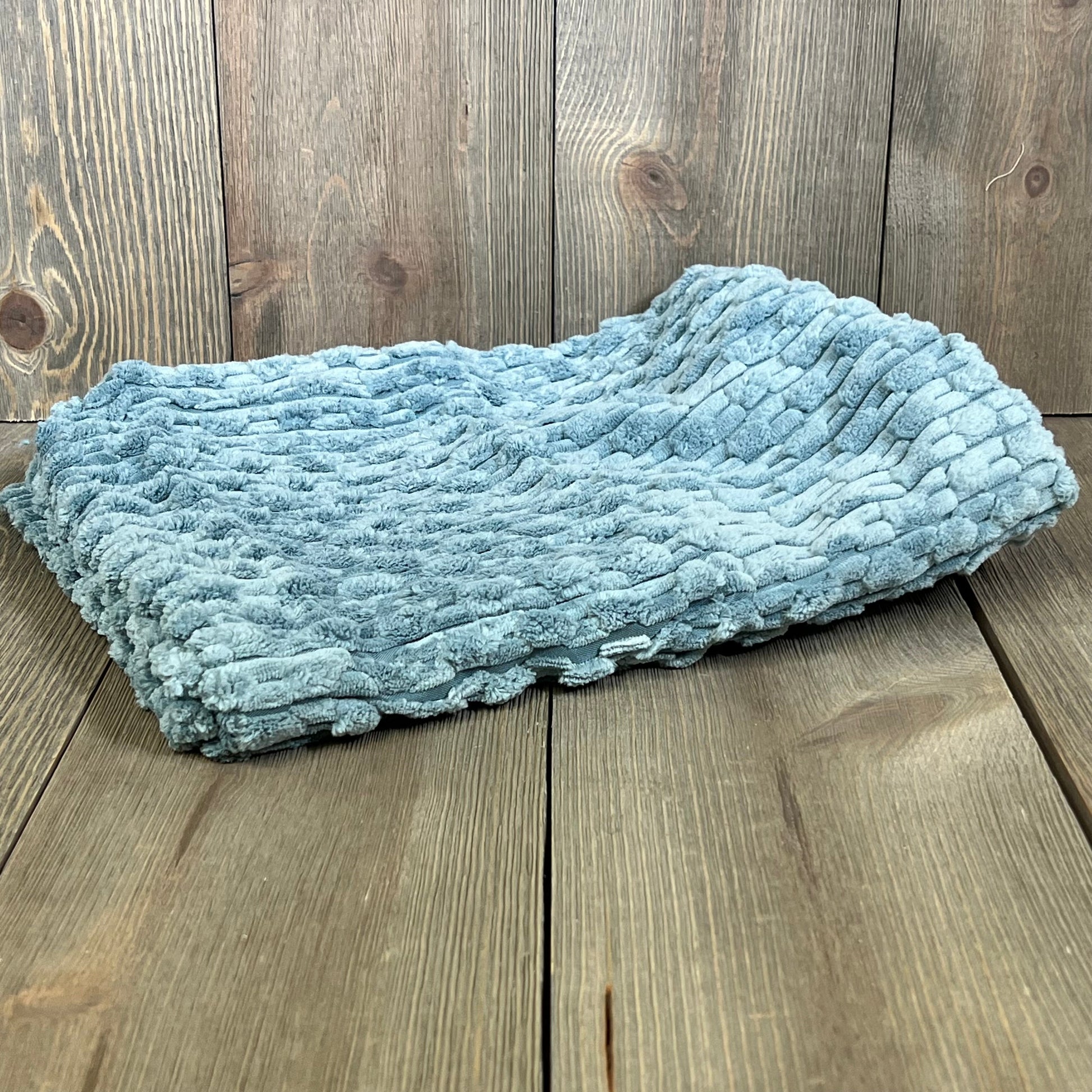Blue grey corduroy pillow cover on wooden surface, ideal for farmhouse decor. Soft texture perfect for couch or bed accents.
