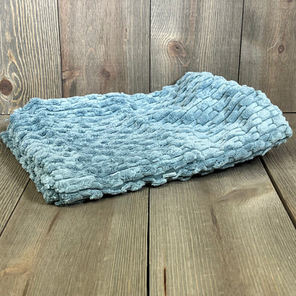 Blue grey corduroy pillow cover on wooden surface, ideal for farmhouse decor. Soft texture perfect for couch or bed accents.