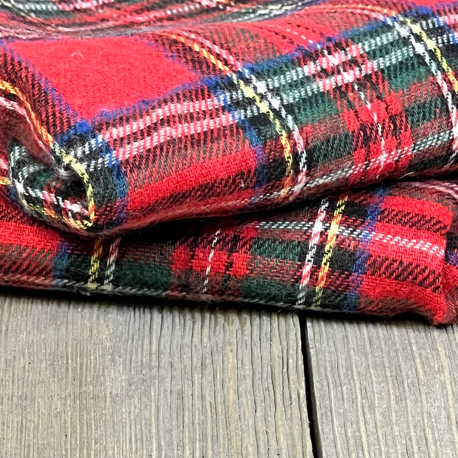 Red Scottish tartan plaid pillow covers, folded on a wooden surface, perfect for festive farmhouse decor.