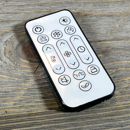 Remote control for Smart Register Booster Fan, featuring multiple function buttons on a rustic wooden surface.