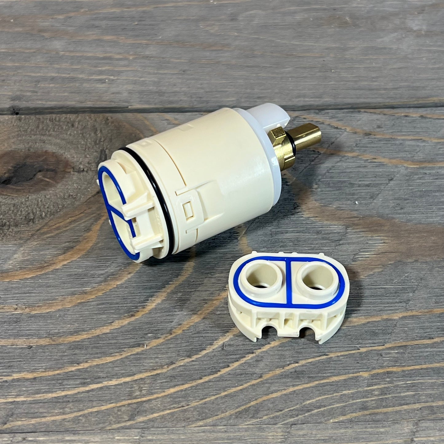 Replacement cartridge and valve assembly for Peerless tub and shower, featuring durable design on wooden surface.