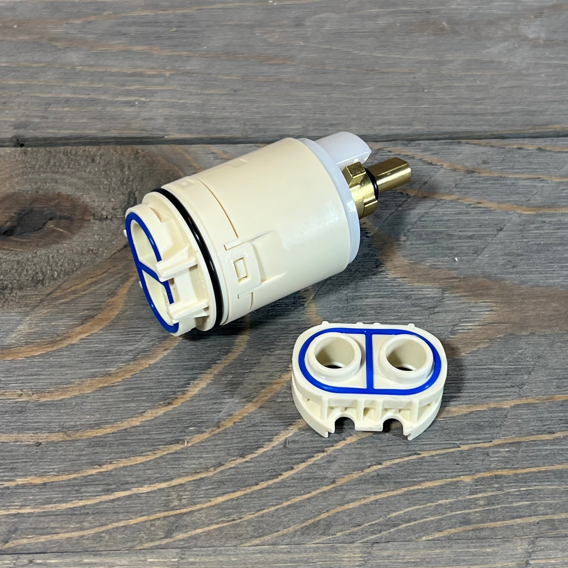 Replacement cartridge and valve assembly for Peerless tub and shower, featuring durable design on wooden surface.