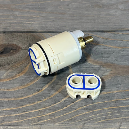 Replacement cartridge and valve assembly for Peerless tub and shower, featuring durable design on wooden surface.