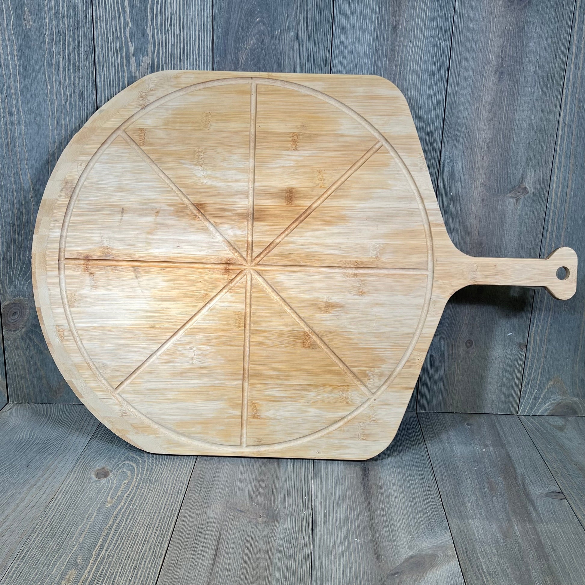 Bamboo pizza peel with 8 slice grooves, ideal for outdoor ovens. Lightweight, smooth 18" paddle perfect for cutting and serving.