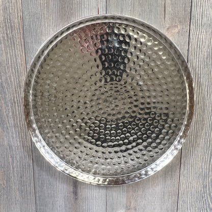 Hammered silver serving tray on wooden table, perfect for candles, jewelry, or food display.
