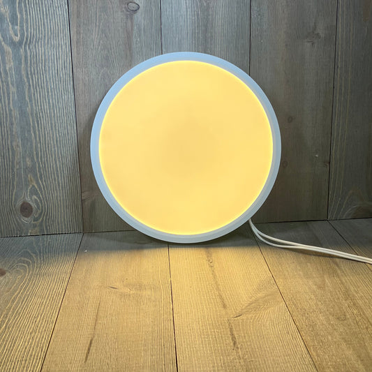 Round Brightever LED flush mount ceiling light, 12-inch, 24W, glowing warm yellow on a wooden floor background.