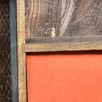 Close-up of rustic wooden texture on GLANT barn door jewelry organizer with vibrant orange interior for earrings and necklaces.